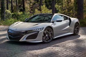 Honda NSX Gris Plata Estacionado sobre una calzada de piedras rodeada de árboles.